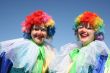 Two bizzare clowns in colored wigs upon blue sky