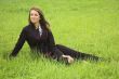 The beautiful girl sits on a green grass