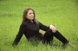 The beautiful girl sits on a green grass
