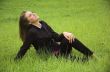 The beautiful girl sits on a green grass