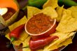 closeup of candle, chips, salsa and peppers