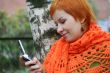 young red-haired woman in red scarf is sms in mobile-phone