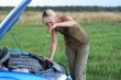 young blond woman with her broken car. The girl is sad