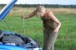 young blond woman with her broken car. The girl is sad