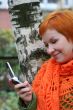 young red-haired woman in red scarf is sms in mobile-phone