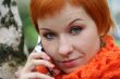 young red-haired woman in red scarf is talking in mobile-phone
