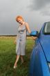Red-haired woman in dress with blue car