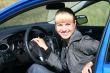 young blond woman in a blue car. She is smiling happy