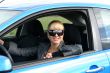 young blond woman in a blue car in sun-glasses
