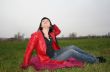 black head woman is sitting on a Plaid in park grass