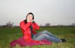 black head woman is sitting on a Plaid in park grass