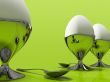 Three eggs and one metallic spoo isolated on green background