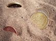 Coins on background with sand