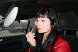 pretty woman using car mirror to apply lipstick