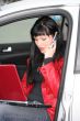 woman is calling by mobile phone and working at laptop in a car