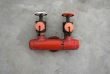 Red iron valve on a concrete wall