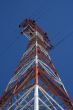 Red and white electricity pylon against the blue sky