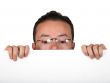 man with glasses peeping over white card