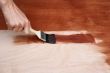 Man`s hand painting a wooden surface
