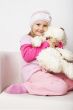 Nice young girl in pink on light background with teddy bear