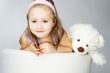 Nice young girl in pink on light background with teddy bear