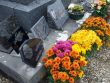 In a cemetery, a gravestone decorated with flowers in autumn