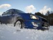 blue car is slipping at snow cavered lake