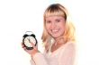 Young blond woman show time on alarm clock. The shot like concept of eve xmas or end of sales