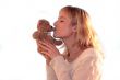 young blond woman is kissing teddy bear