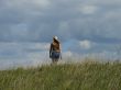 alone female figure in wide field uder cloudy sky