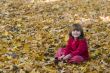 Kid sitting on fallen leaves