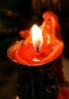 red candle flaming upon dark background