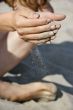 sand dropping down through girl`s fingers