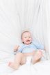 Little joyful baby fall on white bed