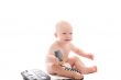 Little smiling baby with telephone receiver in hand over white
