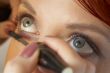 beautician is doing make-up to red-haired woman