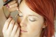 beautician is doing make-up to red-haired woman