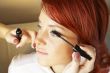 beautician is doing make-up to red-haired woman