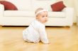 Eight month old baby girl seated on a hardwood floor