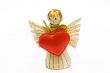 The angel made of straw, with the big gold bow and red heart in