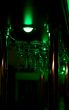 Glasses hang above a bar in green lighting