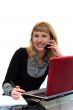 woman is writing and calling by phone sitting near laptop