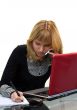 woman is writing and calling by phone sitting near laptop