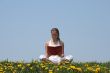 Young woman reading a book in a flowering field