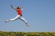 Girl flying in a jump over flowering field