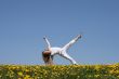 Smiling young woman exercising in dandelion field