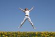 Smiling girl jumping in flowering meadow