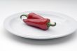 Two red chile peppers on a white plate