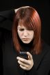 Girl scratching head while checking her mobile phone