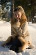 Young beautiful girl sitting on snow in wood.